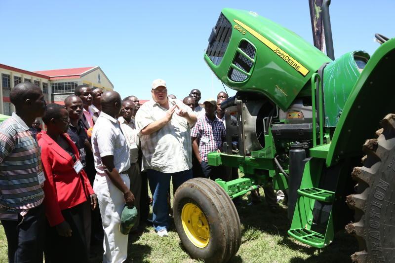 Farmers gathered around modern tractor machinery during a live demonstration